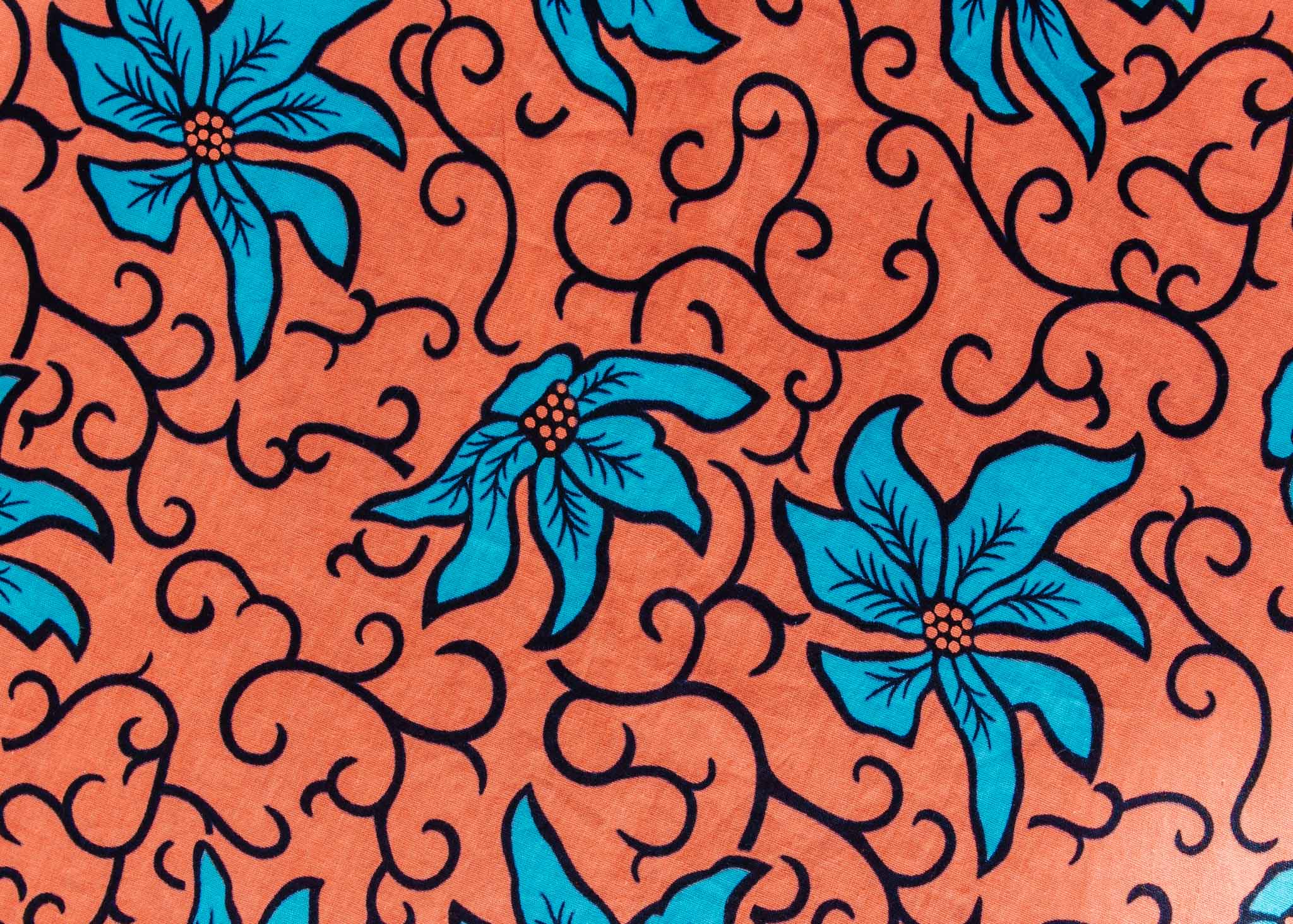 Close up display of orange dress with teal floral print, fabric.