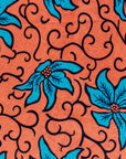 Close up display of orange dress with teal floral print, fabric.