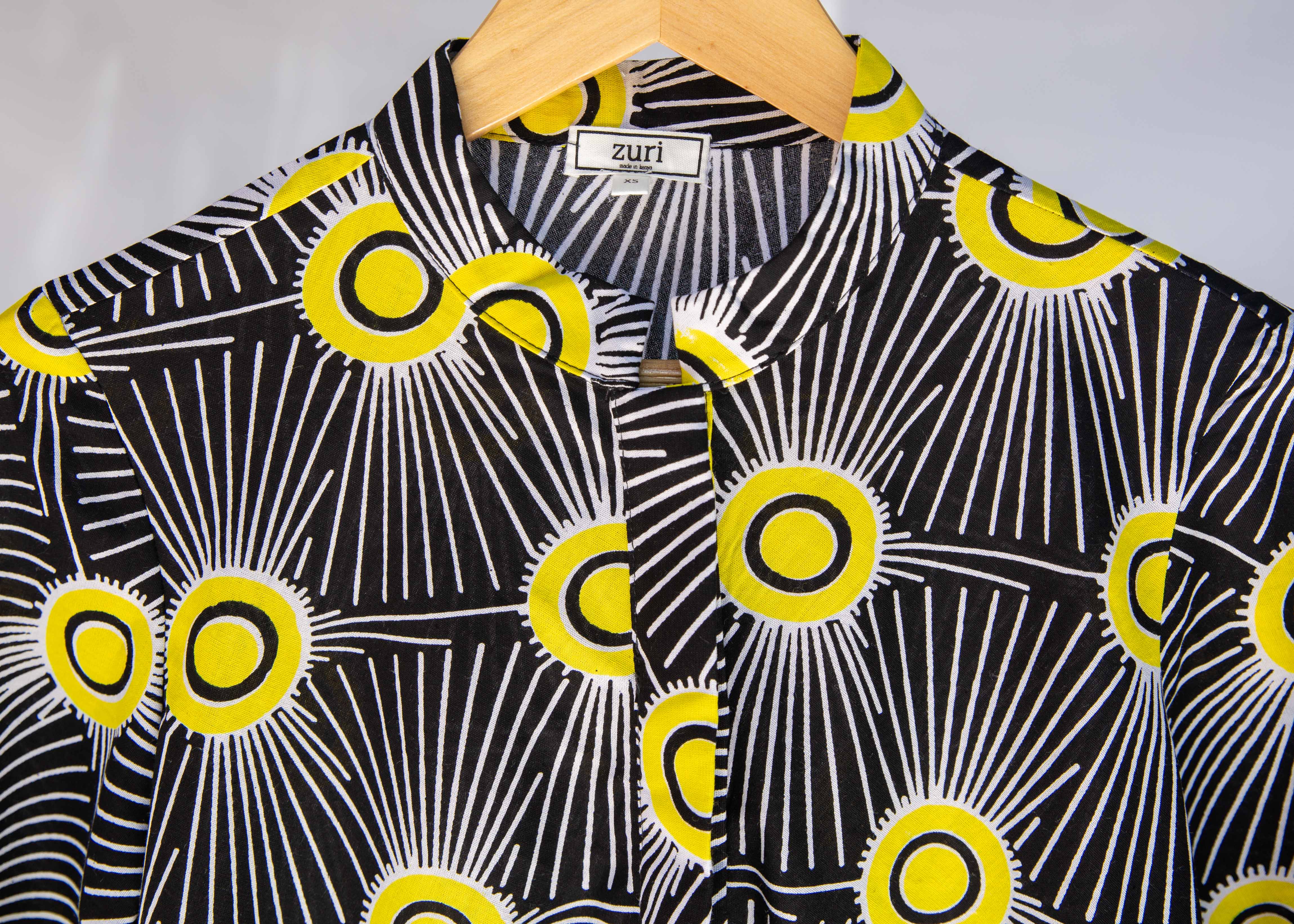 Display of Model wearing black and white dress with yellow burst print.