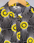 Display of Model wearing black and white dress with yellow burst print.