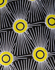 Close up display of Model wearing black and white dress with yellow burst print, fabric.