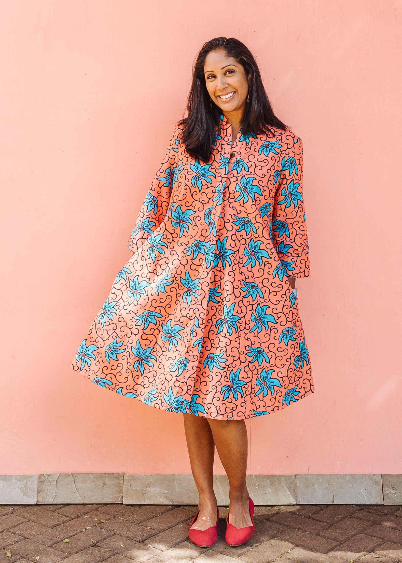 Model wearing orange dress with teal floral print.