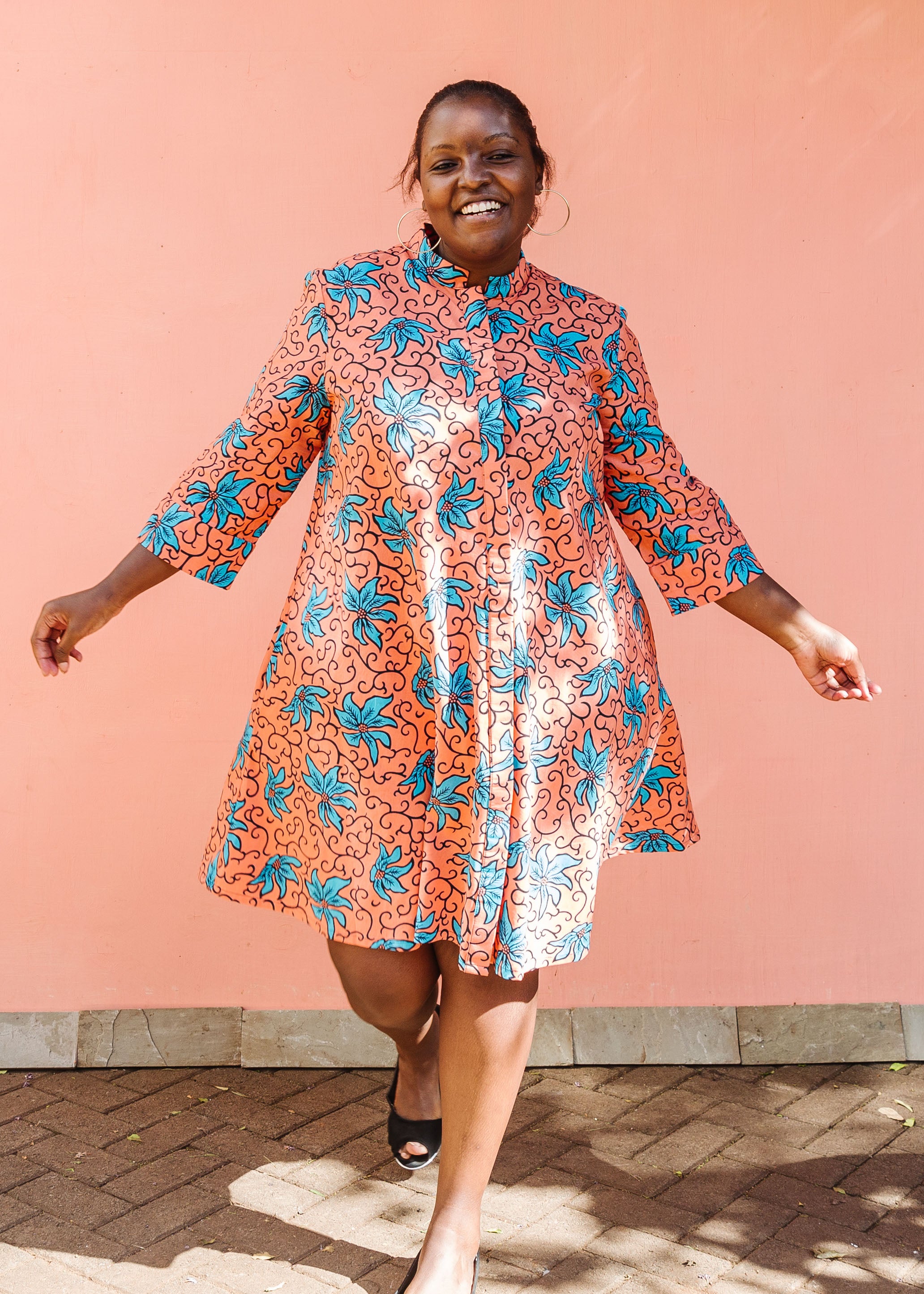 Model wearing orange dress with teal floral print.