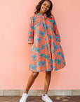 Model wearing orange dress with teal floral print.