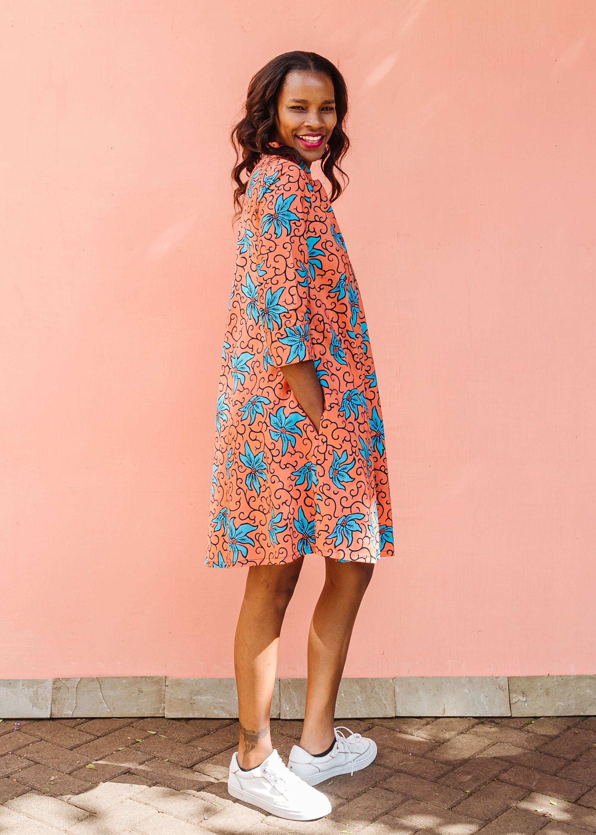 Model wearing orange dress with teal floral print.