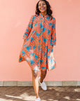 Model wearing orange dress with teal floral print.