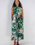 Model wearing dress with green, grey, white, orange and black abstract print.