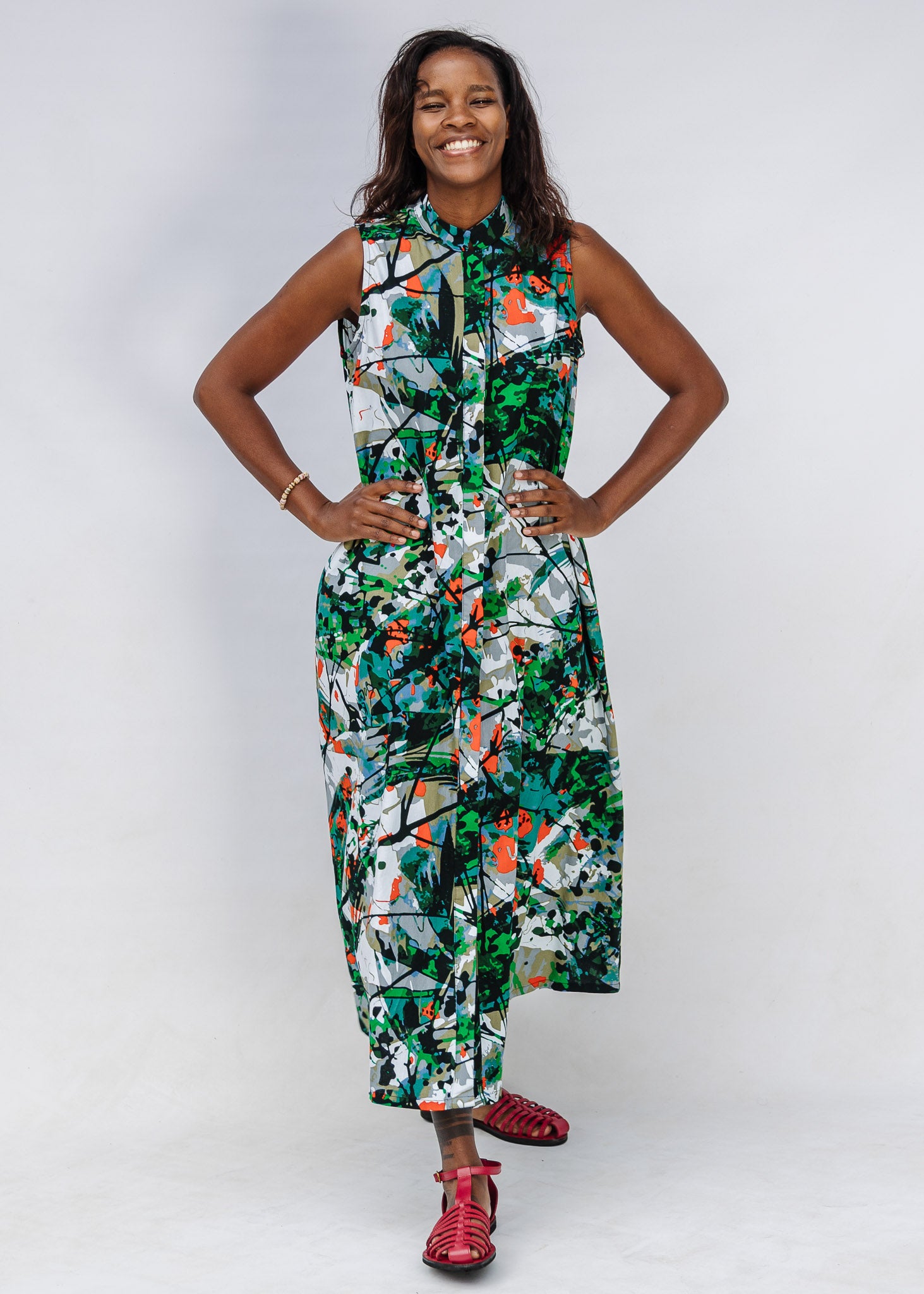 Model wearing dress with green, grey, white, orange and black abstract print.