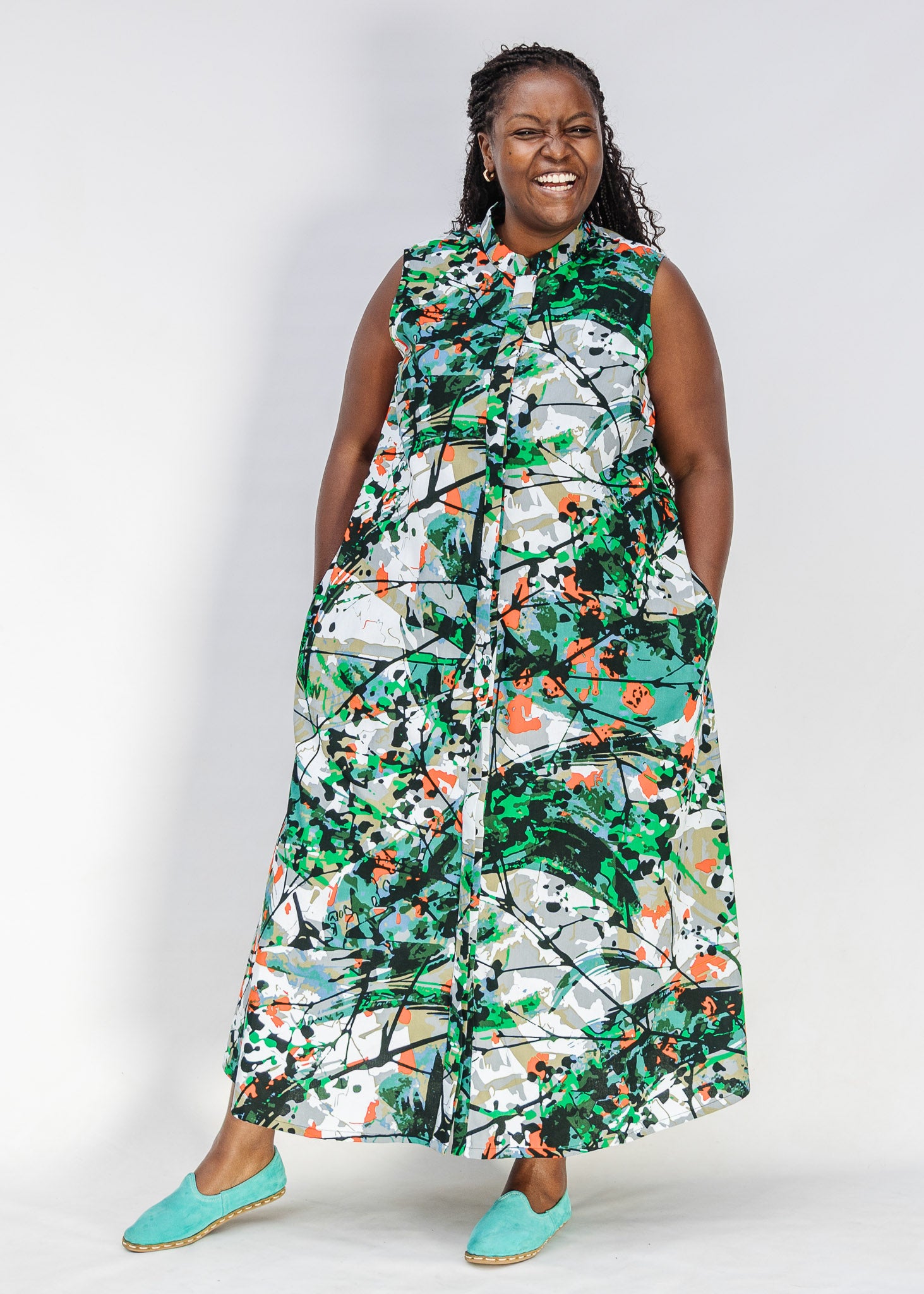 Model wearing dress with green, grey, white, orange and black abstract print.