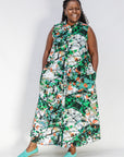 Model wearing dress with green, grey, white, orange and black abstract print.