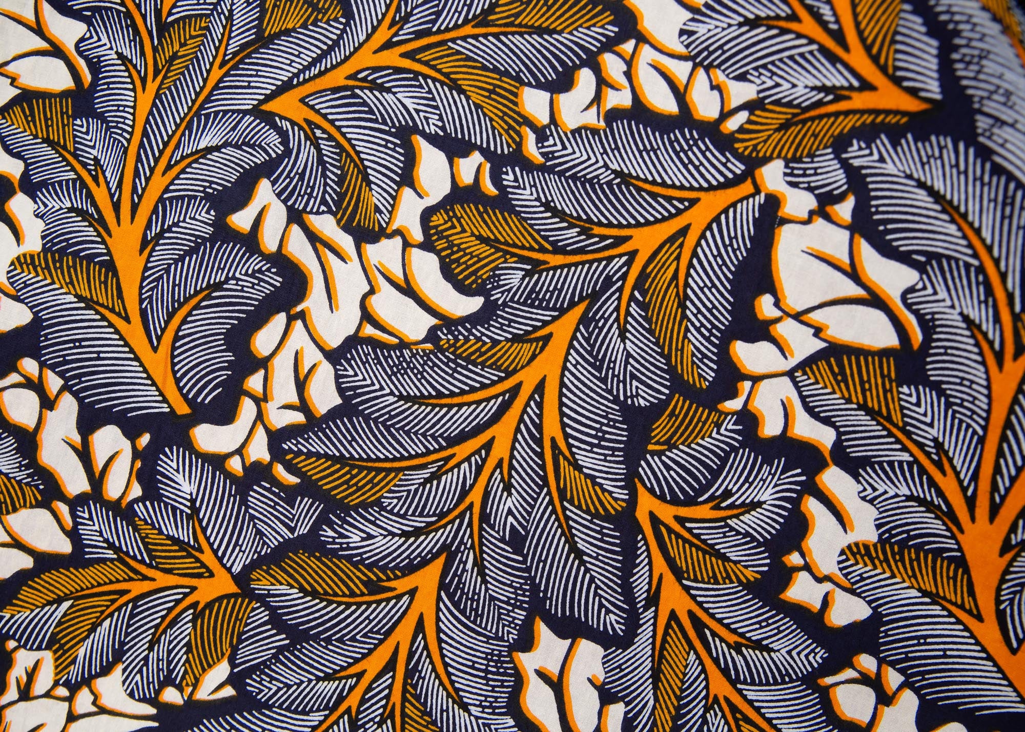 Close up display of orange, navy blue and cream kale leaf print