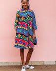 The model is wearing colorful mandala print dress