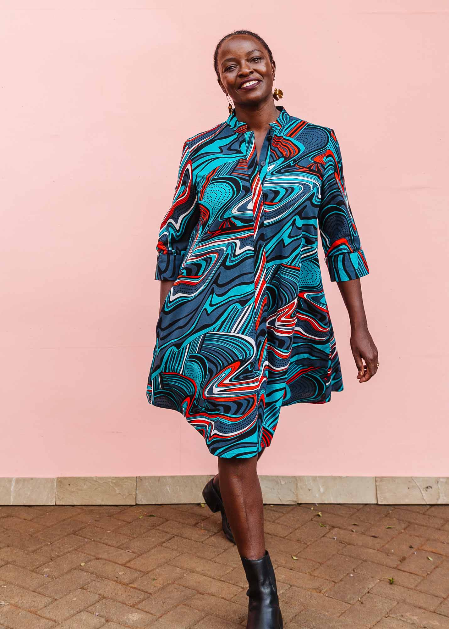 The model is wearing turquoise, black, slate, white and red abstract print dress