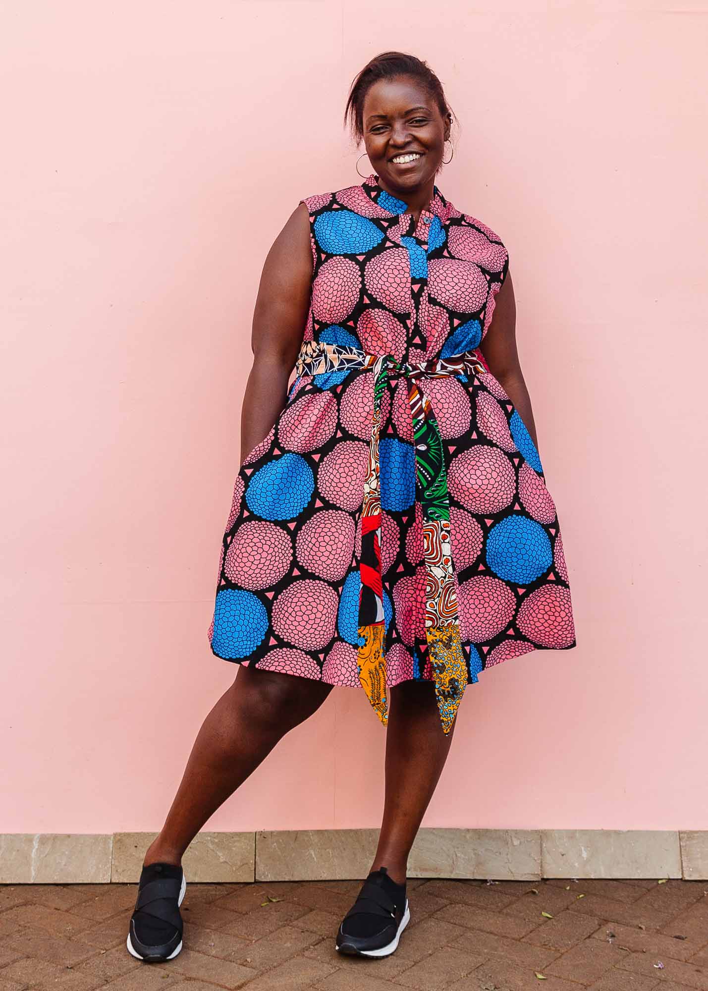 The model is wearing coral, blue and black circular print dress