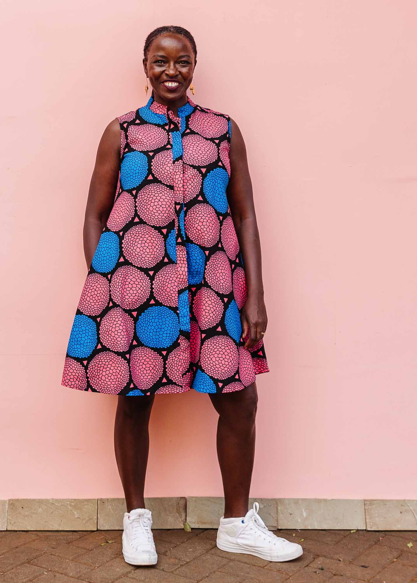 The model is wearing coral, blue and black circular print dress