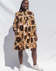 The model is wearing navy, black, off white, yellow flower print dress 