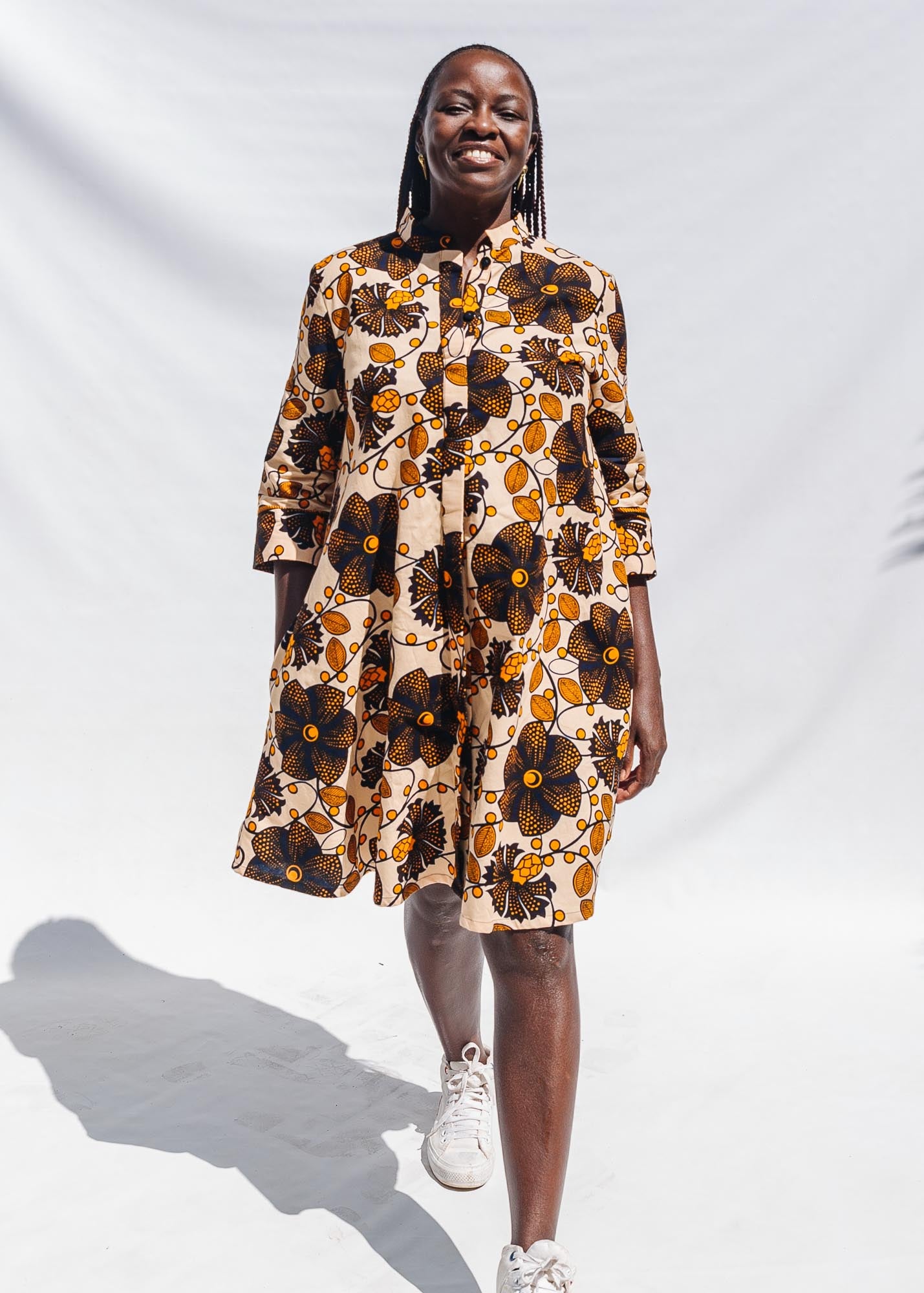 The model is wearing navy, black, off white, yellow flower print dress 