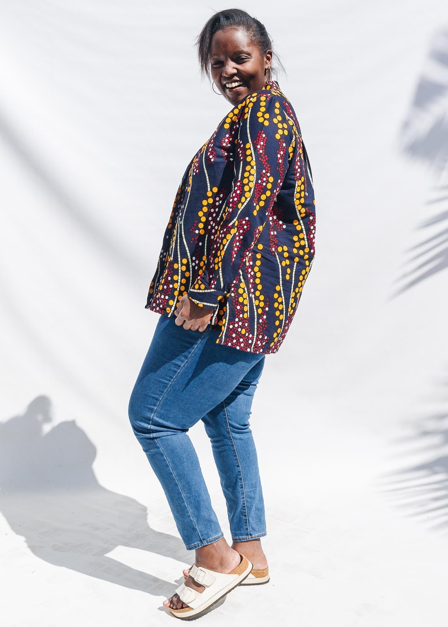  The model is wearing navy, yellow, white, red print shirt