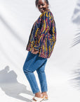  The model is wearing navy, yellow, white, red print shirt