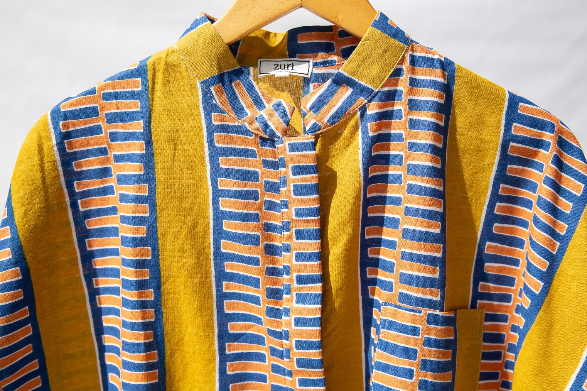 Display of olive-yellow, blue, orange and white geometric printed shirt