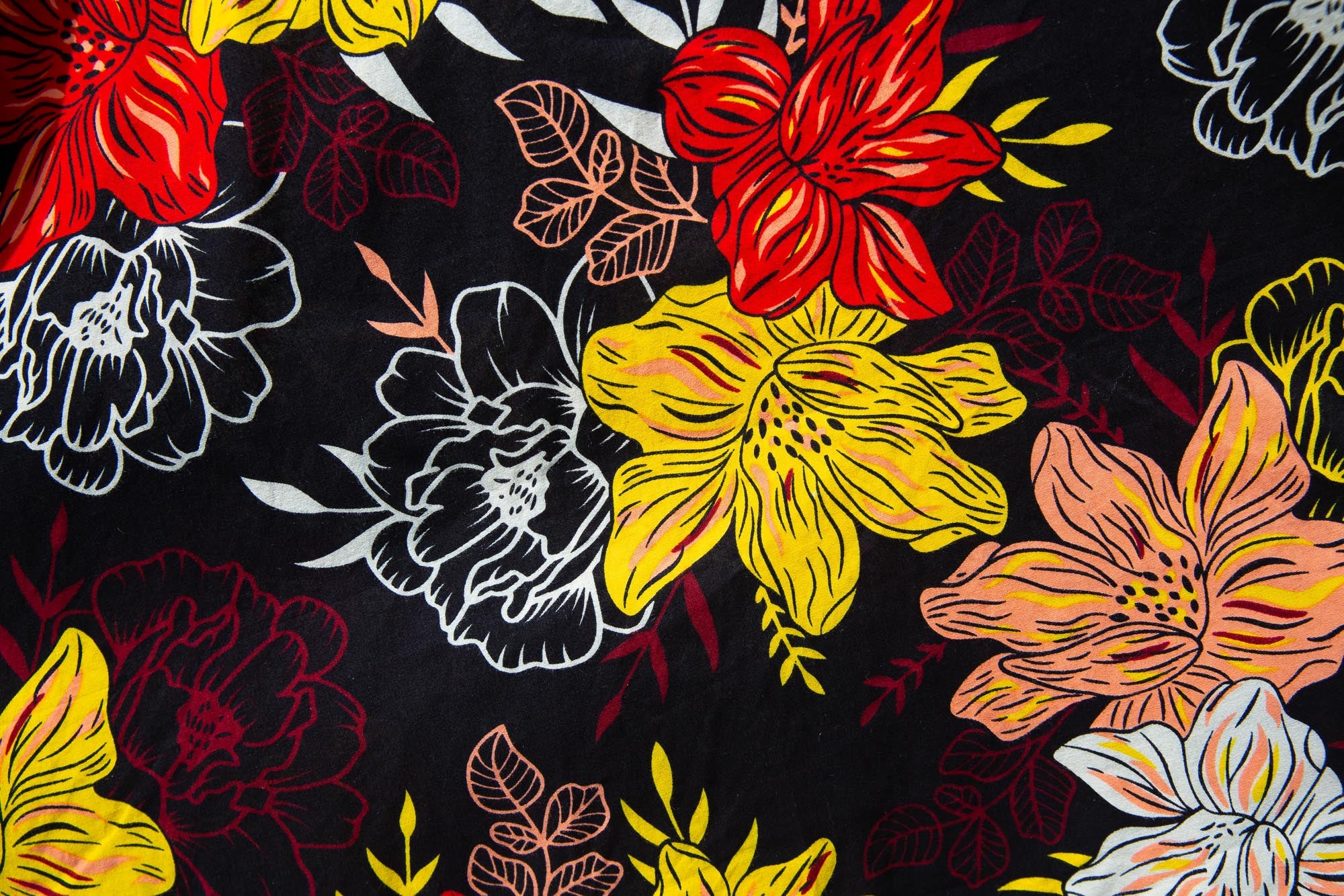 Close up display of black, white, red, yellow, peach floral print dress