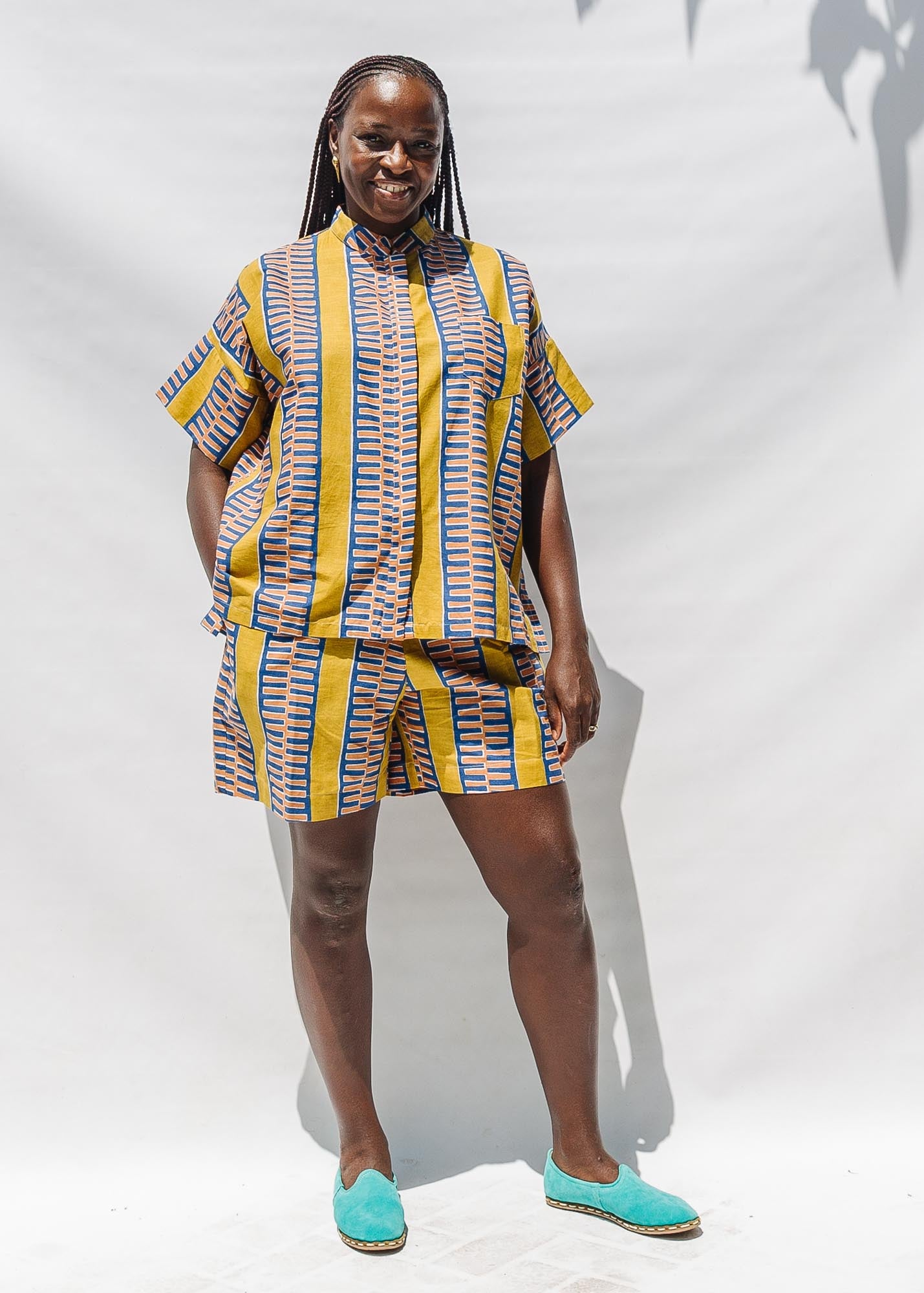 The model is wearing olive-yellow, blue, orange and white geometric printed shirt