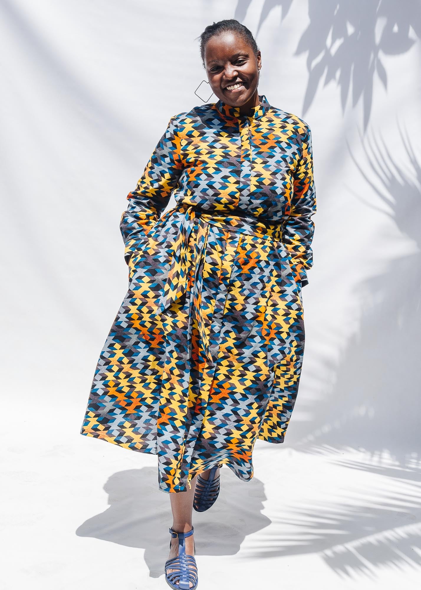 The model is wearing colorful geometric print dress