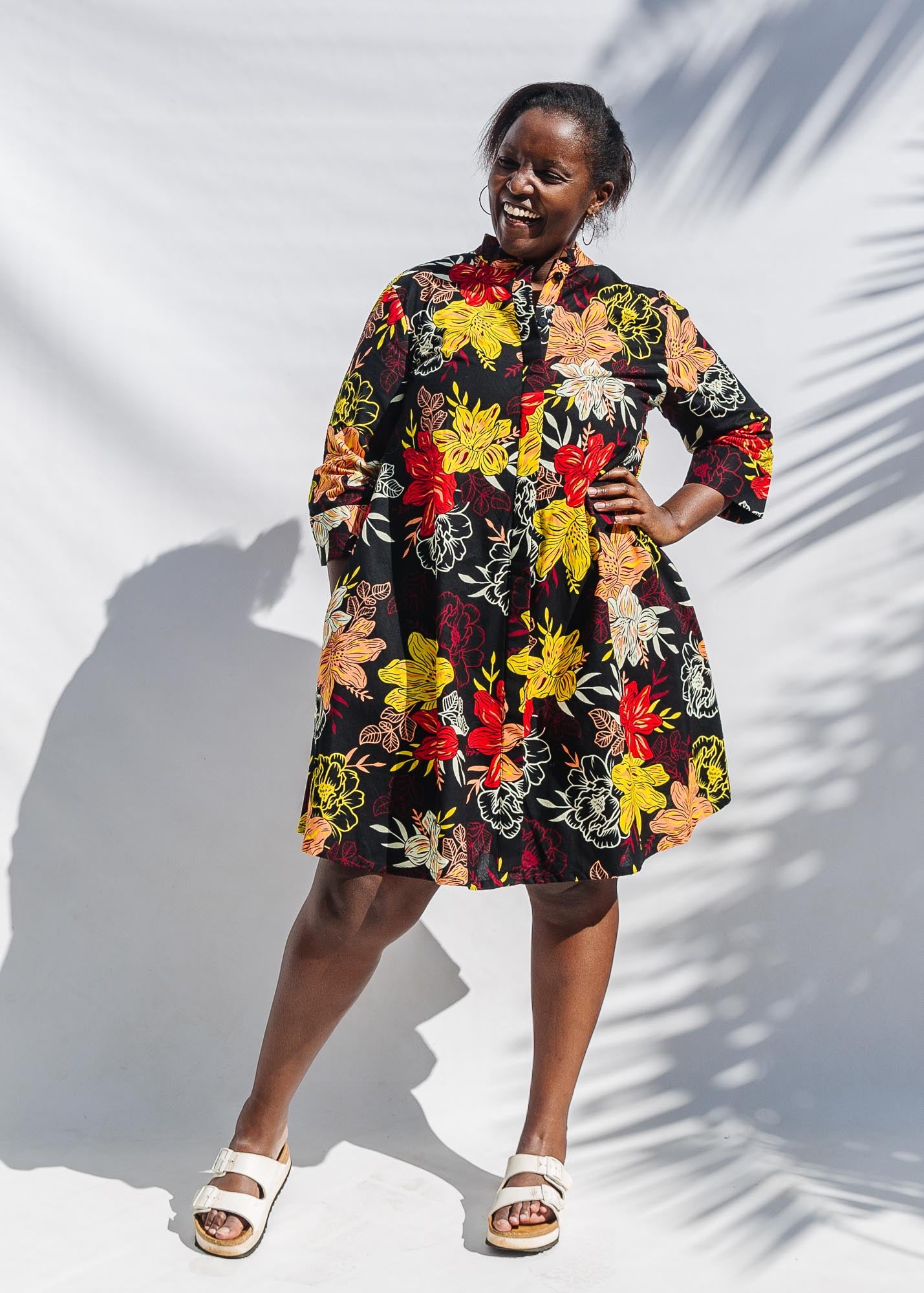 The model is wearing black, white, red, yellow, peach floral print dress