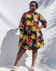 The model is wearing black, white, red, yellow, peach floral print dress