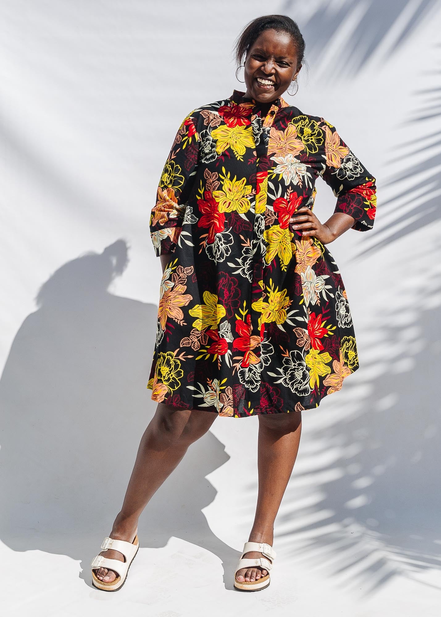 The model is wearing black, white, red, yellow, peach floral print dress