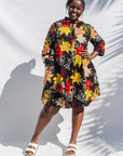 The model is wearing black, white, red, yellow, peach floral print dress