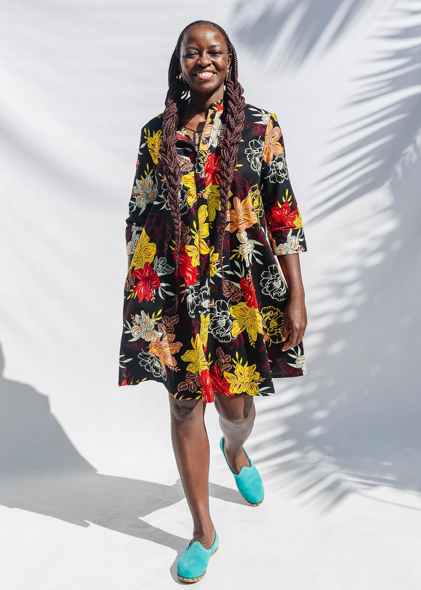 The model is wearing black, white, red, yellow, peach floral print dress