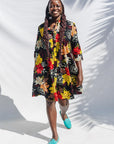 The model is wearing black, white, red, yellow, peach floral print dress