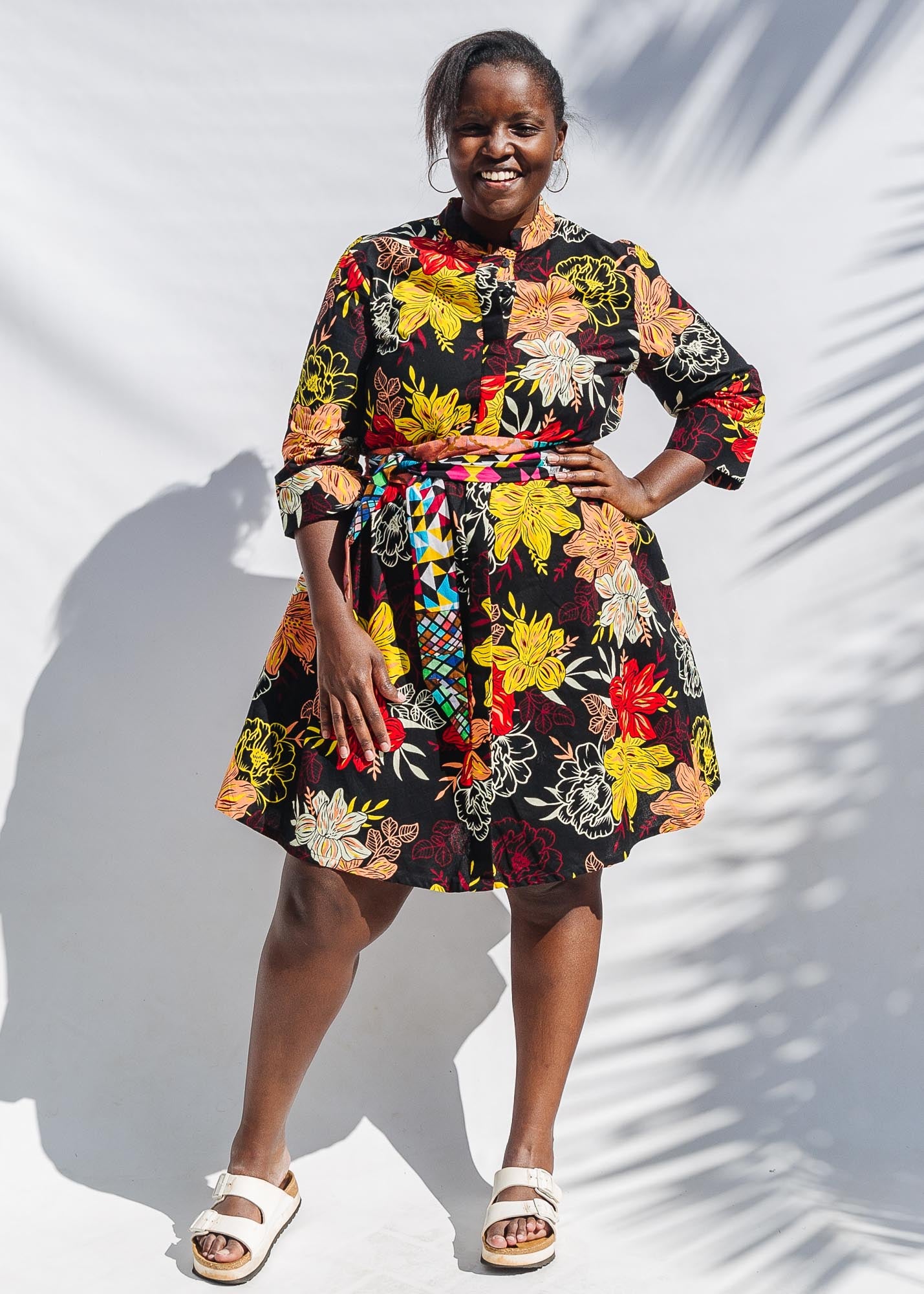 The model is wearing black, white, red, yellow, peach floral print dress