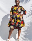 The model is wearing black, white, red, yellow, peach floral print dress