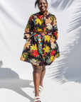 The model is wearing black, white, red, yellow, peach floral print dress