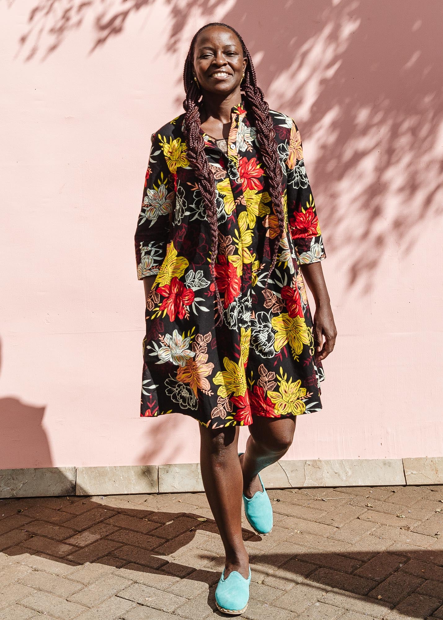 The model is wearing black, white, red, yellow, peach floral print dress