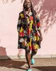 The model is wearing black, white, red, yellow, peach floral print dress