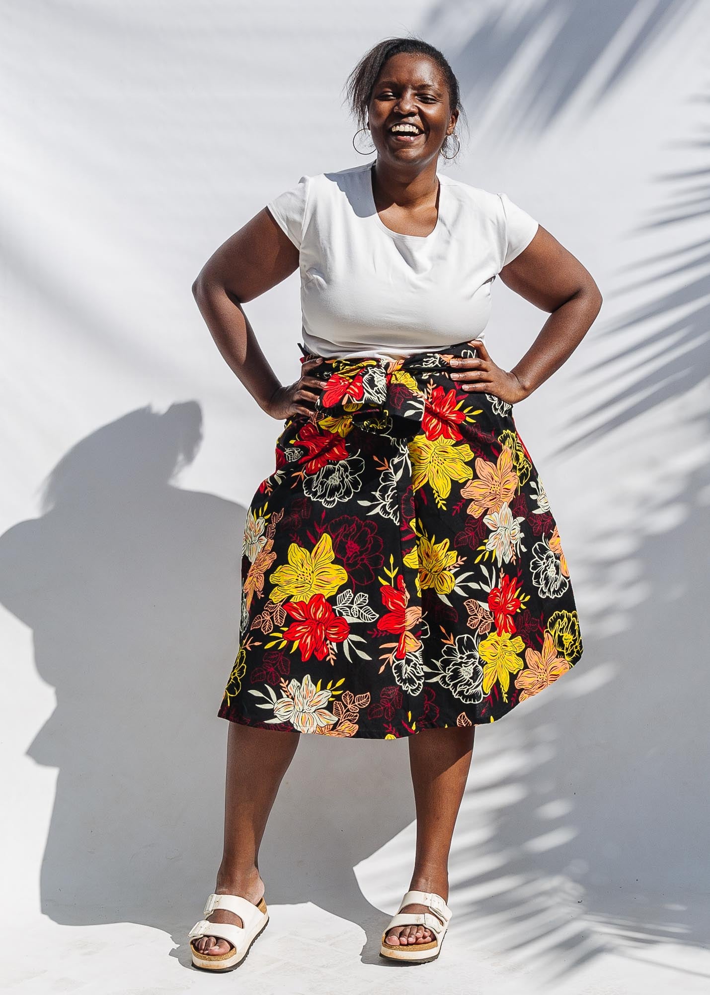 The model is wearing black, white, red, yellow, peach floral print dress