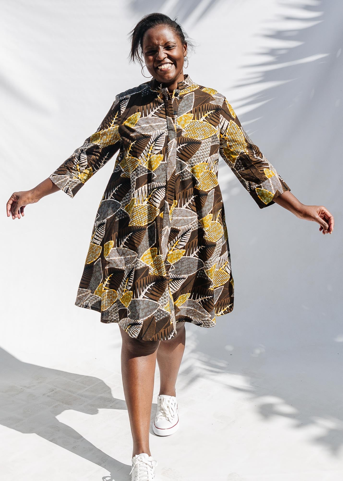 The model is wearing black, brown, yellow, beige print dress 