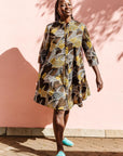 The model is wearing black, brown, yellow, beige print dress 