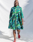 The model is wearing black, green, white, blue and aqua print dress