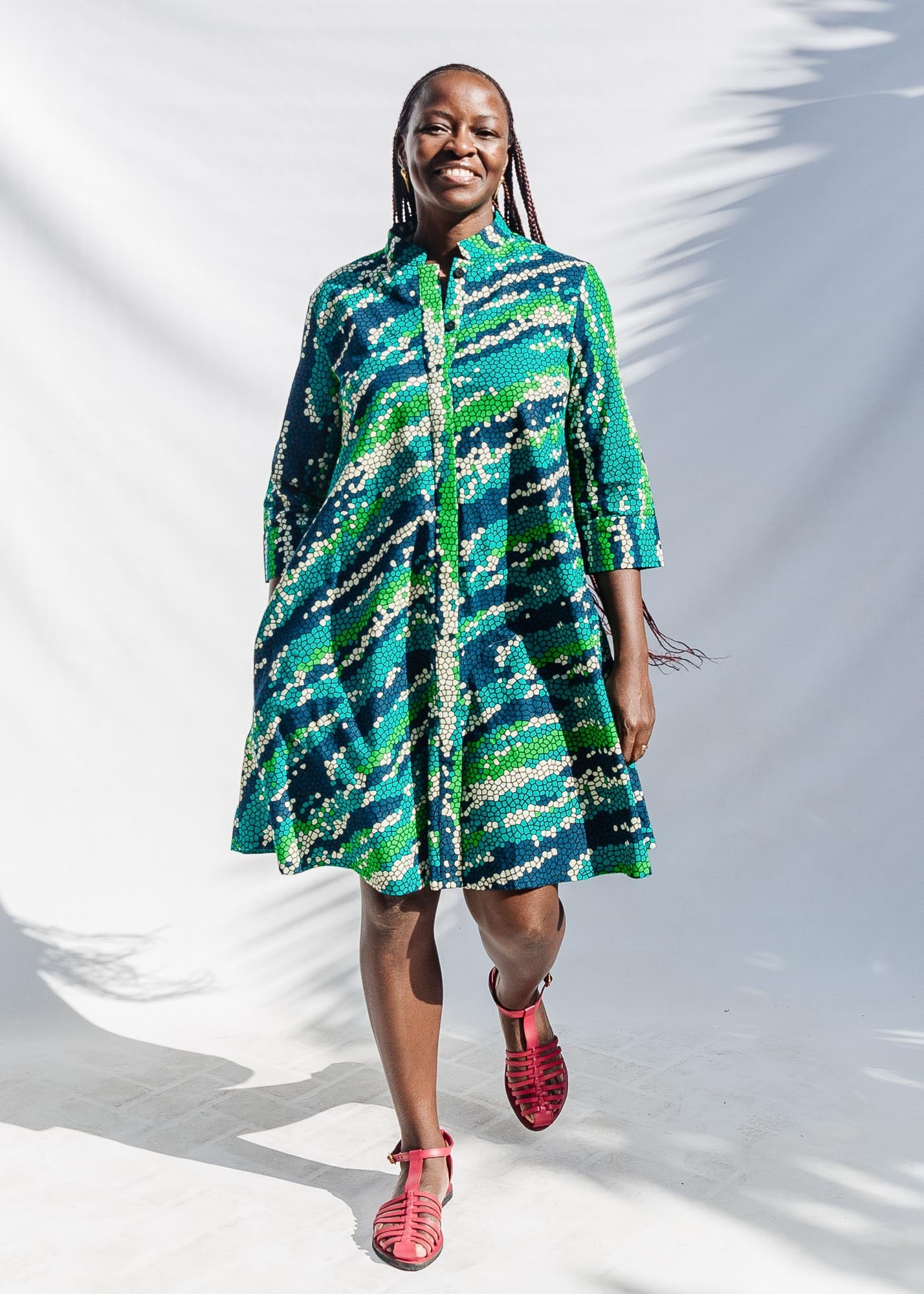 The model is wearing black, green, white, blue and aqua print dress