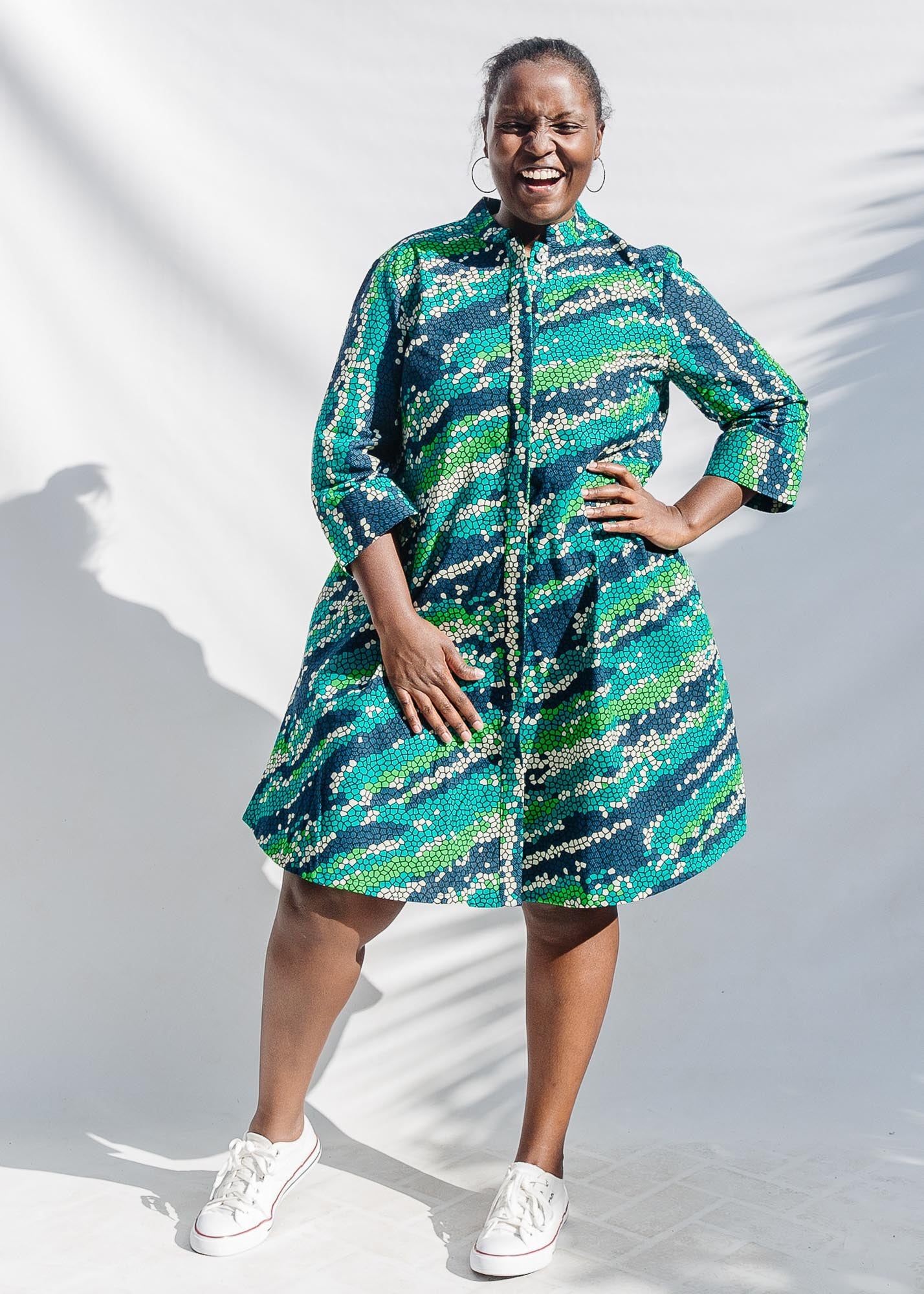 The model is wearing black, green, white, blue and aqua print dress