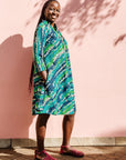 The model is wearing black, green, white, blue and aqua print dress