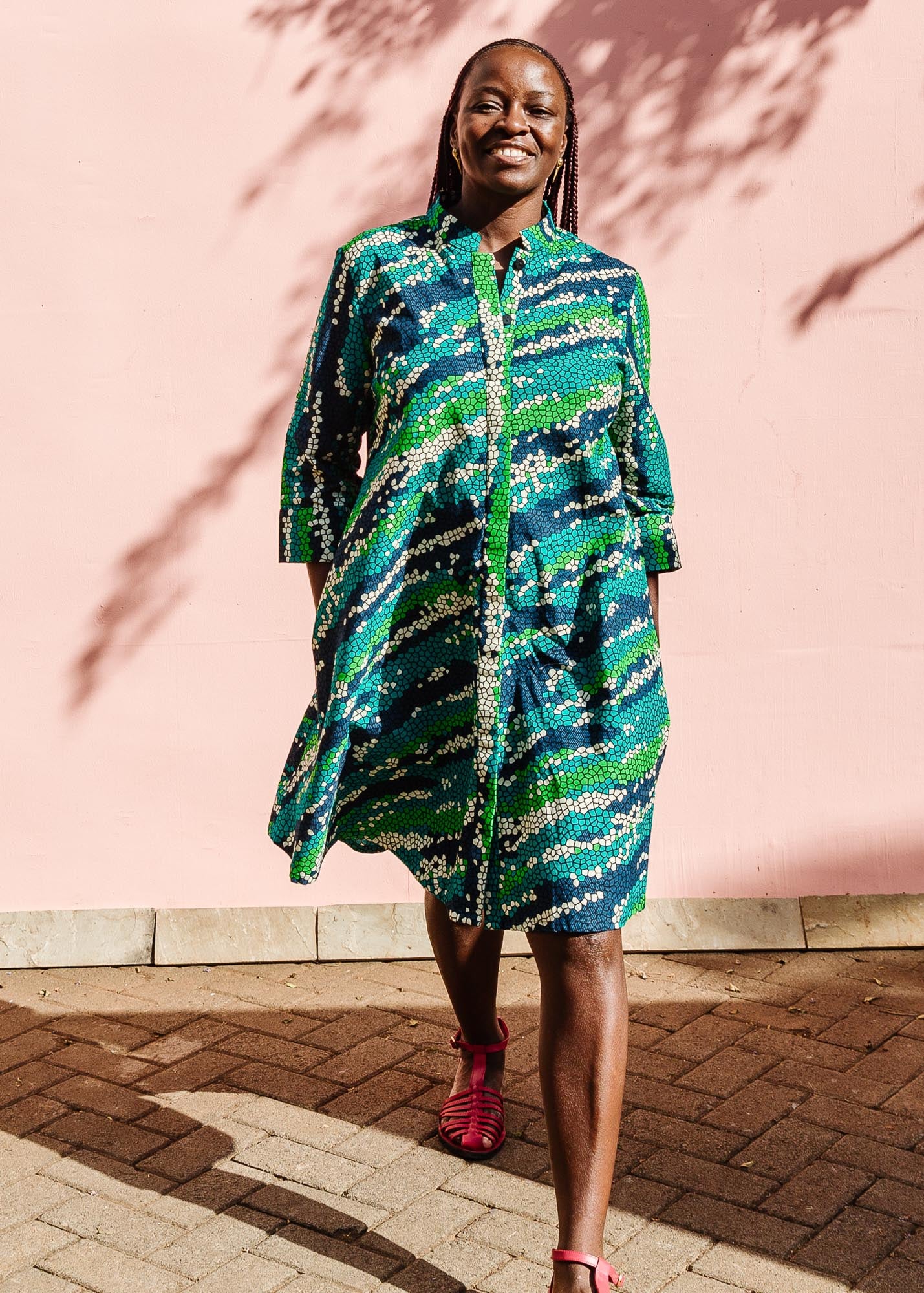 The model is wearing black, green, white, blue and aqua print dress