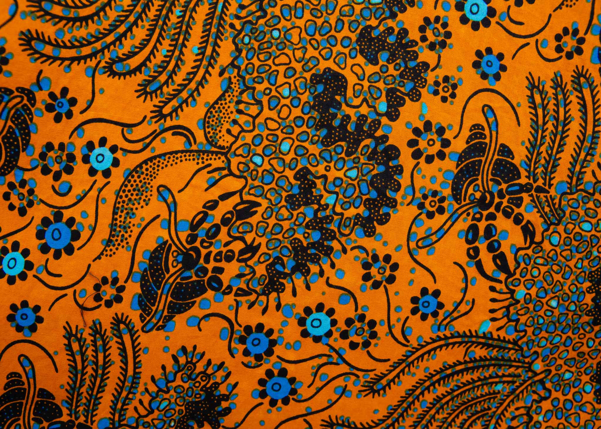 Close up display of caramel dress with blue and black small floral print, fabric.