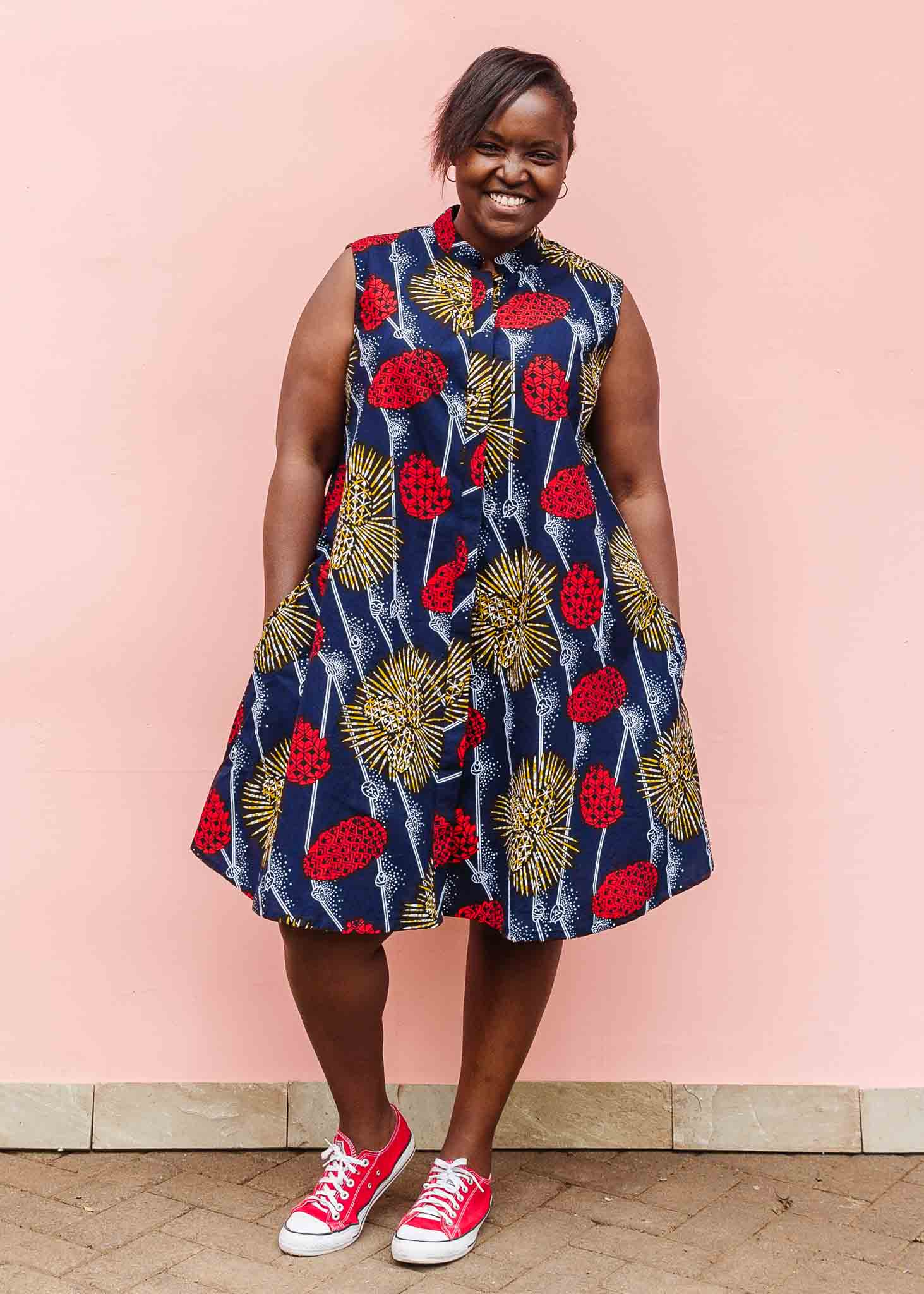 Model wearing navy sleeveless dress with red, yellow and white splatter print.