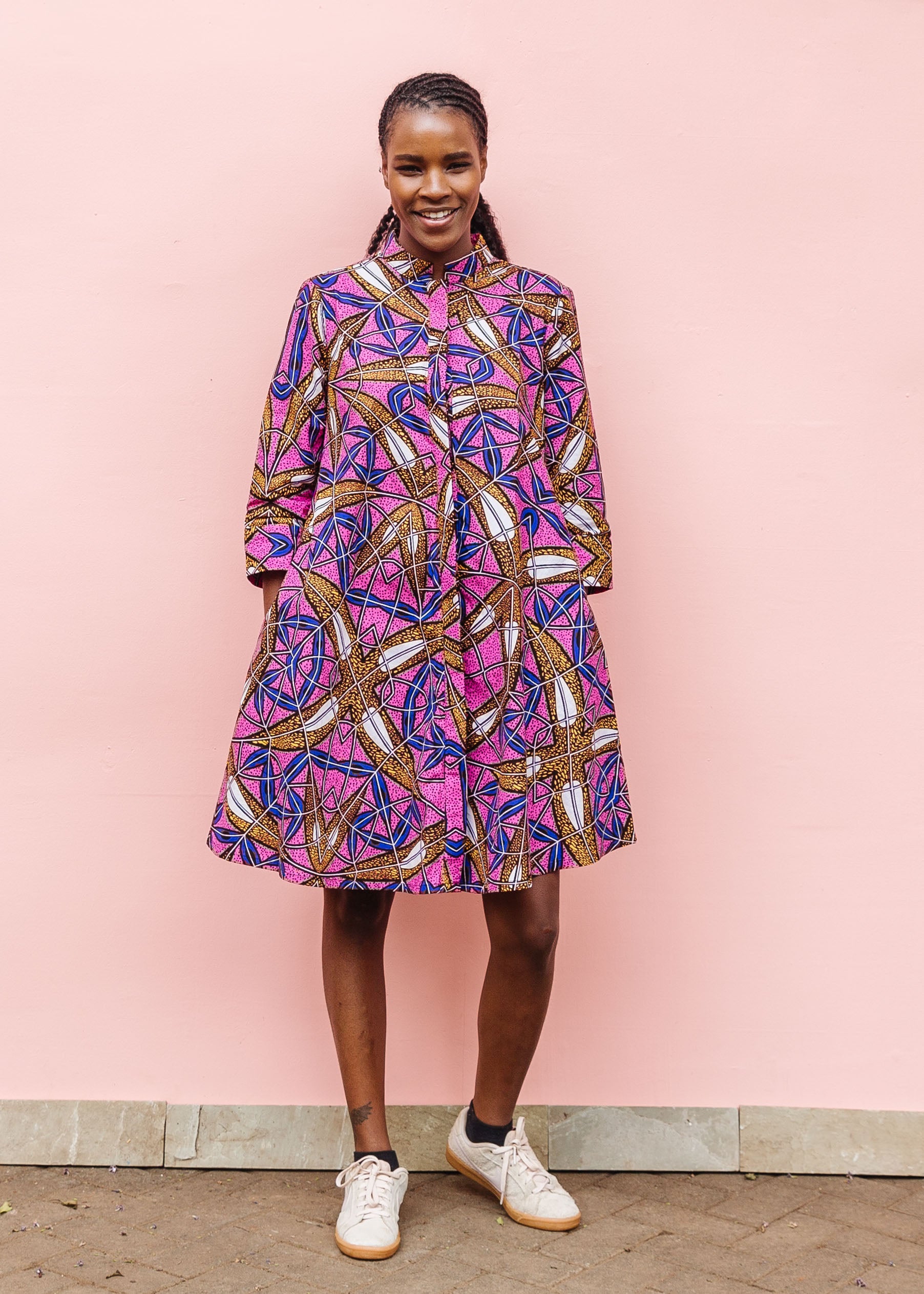 Model wearing a pink dress with floral yellow, blue and white print.