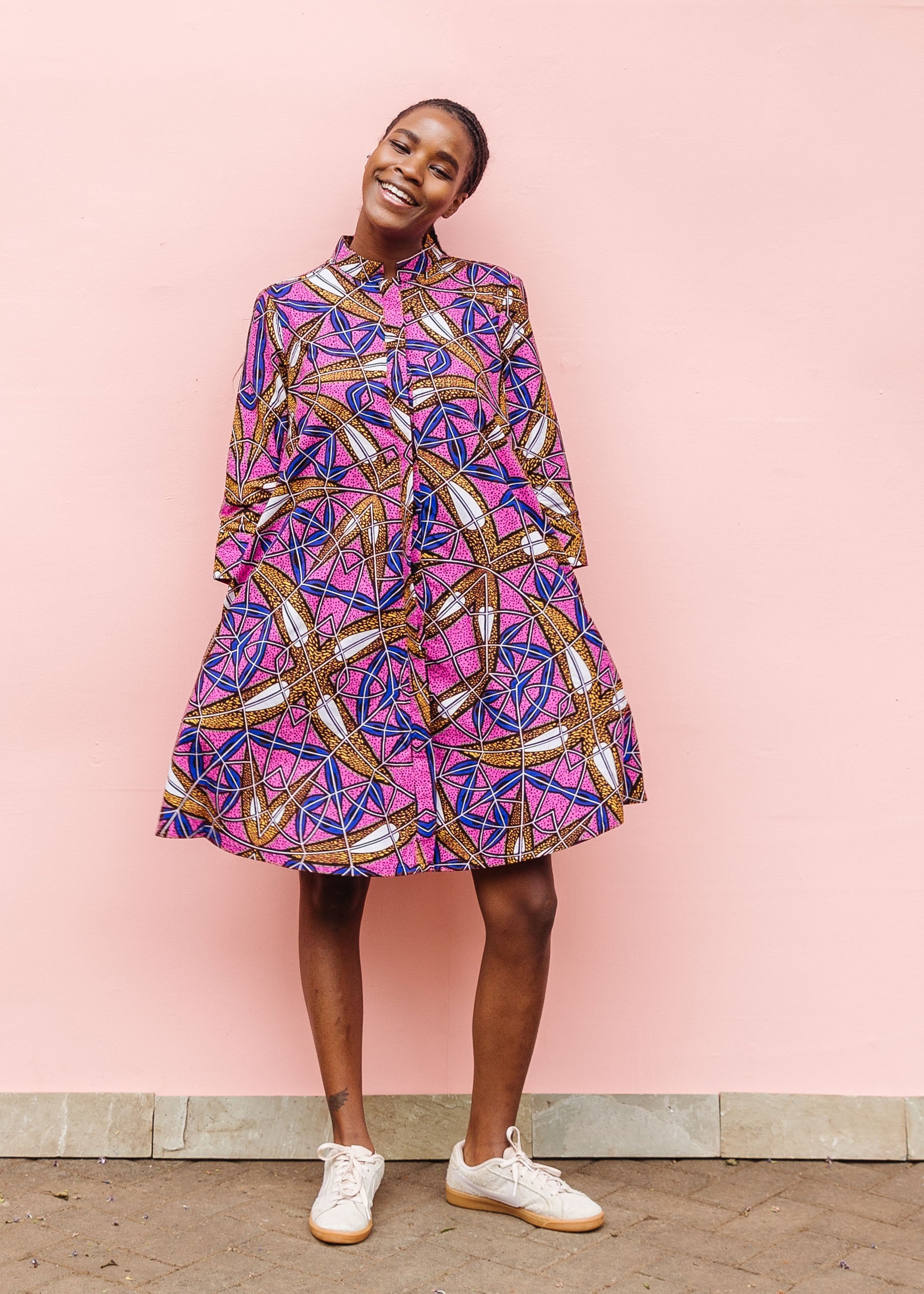 Model wearing a pink dress with floral yellow, blue and white print.